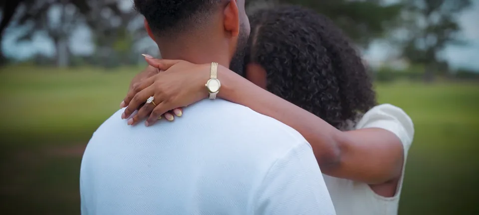 An embrace, the ring on her hand at his shoulder