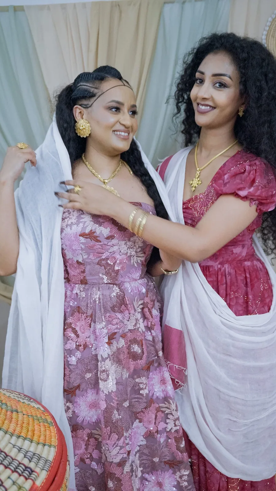 Two women adjusting a white shawl together