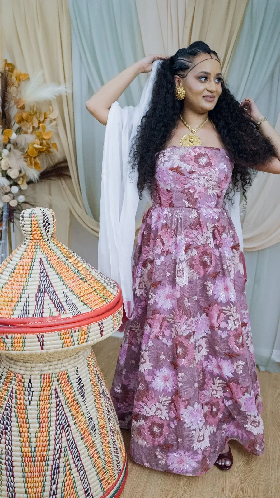Hands to the hair, turning to camera against the draped backdrop