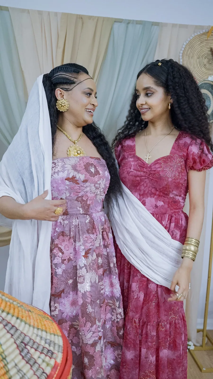 Two women standing side by side, one in a white shawl