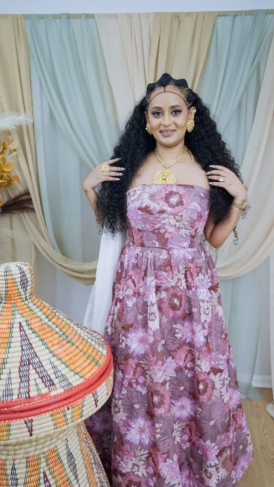 Full-length portrait beside a woven mesob basket