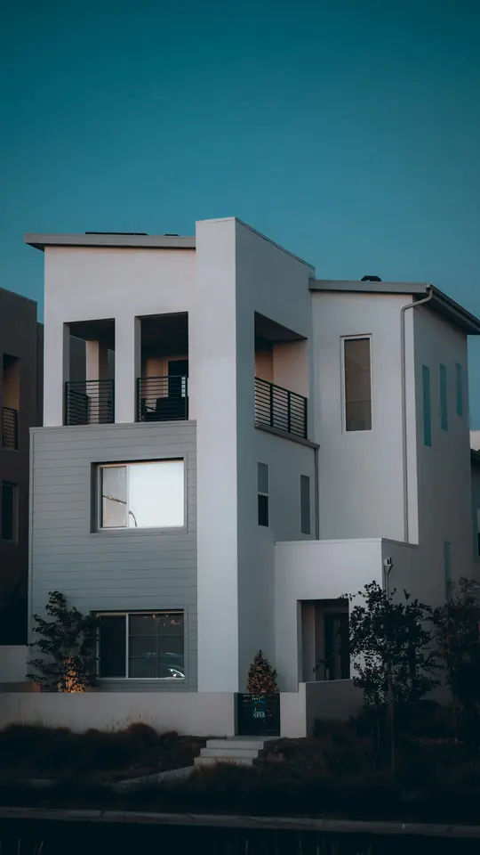 A modern three-story house at dusk, framed vertically the way a listing reel shows it.